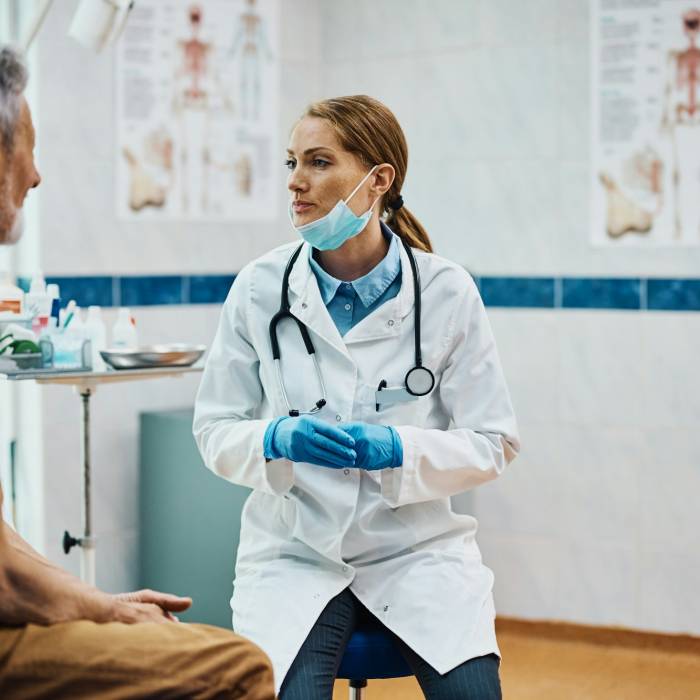 Female cardiologist communicating with mature patient at doctor's office.