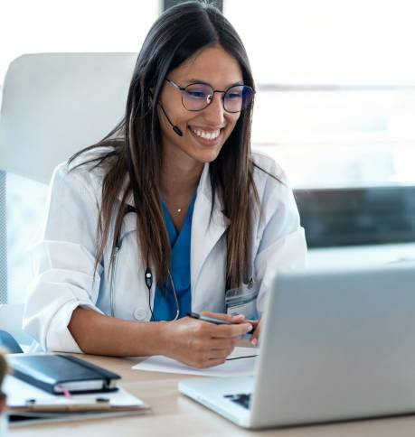 Female doctor talking with colleagues through a video call with a laptop in the consultation.