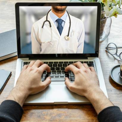 Telemedicine concept. Doctor GP on a computer screen, office desk background